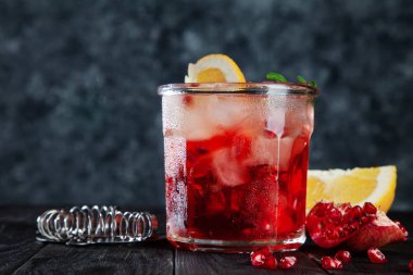 Görünümü üzerinde kırmızı alkollü kokteyl kadar lezzetli yakın. Koyu ahşap arka plan üzerinde buz, İçecek, limon ve bar gereçleri ile cam. Kopya metin, logo veya marka için boş alan.