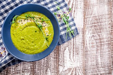 Vejetaryen yeşil bezelye çorbası microgreen mavi kumaş ve ahşap beyaz arka plan ile. Üstten görünüm vegan gıda. Sağlıklı ev yapımı vegan yemek veya aperatif. Logo, metin ya da marka için boş alanı Kopyala.