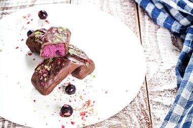 Kaju ve yaban mersini çubuğundaki görünümü kadar karoba yapılan bir sır ile kapatın. Vegan kek mavi kumaş ve ahşap beyaz arka plan üzerine. Sağlıklı ev yapımı vegan yemek veya aperatif. Boş alan için metin, kopyalama logosu