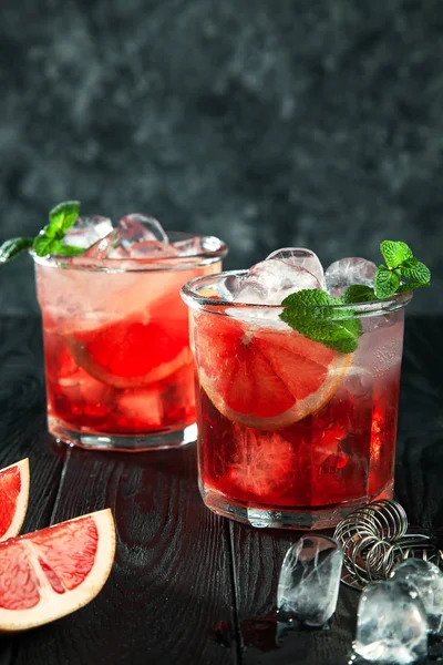 美味的亲密景色 可以欣赏到来自红莓的红色新鲜酒精鸡尾酒 玻璃与冰 柚子和酒吧用具在黑暗的木制背景 复制文本 徽标或品牌的可用空间 — 图库照片