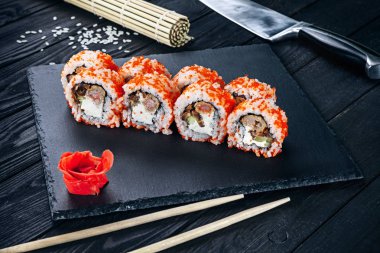 Suşi rulo ile kırmızı balık, bamya ve Philadelphia peynir ile siyah kömür Yönetim Kurulu ve ahşap arka plan görünümünü kapatın. Geleneksel Japon mutfağı. Metin, kopya boş alan ile gıda logosu.