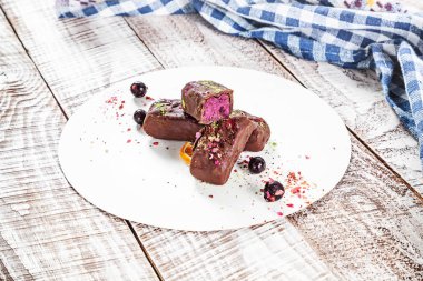 Kaju ve yaban mersini çubuğundaki görünümü kadar karoba yapılan bir sır ile kapatın. Vegan kek mavi kumaş ve ahşap beyaz arka plan üzerine. Sağlıklı ev yapımı vegan yemek veya aperatif. Boş alan için metin, kopyalama logosu