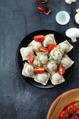 Üstten görünüm taze ravioli ile dilim kiraz domates, mantar ve otlar siyah saç ve koyu arka plan üzerinde. Metin için özgür kopya yer. Restoran, yemek menüsü, yemek tarifi, Cafe konsept. İtalyan mutfağı.