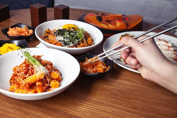 Male hand holds Chinese food with chopsticks. Close up view on traditional chinese cuisine. Restaurant, food menu, recipe, cafe concept. Food party. Korean cuisine. Free copy space. Lifestyle food
