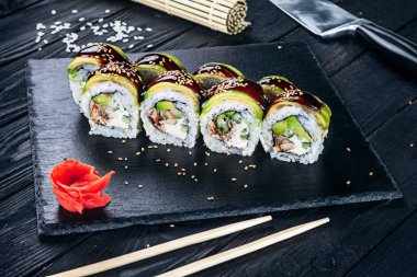 Suşi rulo siyah taş çubuklarla servis. Suşi koyu arka plan üzerinde görünümü kapatın. Geleneksel Japon mutfağı. Restoran, yemek menüsü, yemek tarifi, Cafe konsept. Kopya alanı sayesinde Live tarzı
