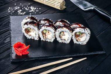 Suşi rulo siyah taş çubuklarla servis. Suşi koyu arka plan üzerinde görünümü kapatın. Geleneksel Japon mutfağı. Restoran, yemek menüsü, yemek tarifi, Cafe konsept. Kopya alanı sayesinde Live tarzı