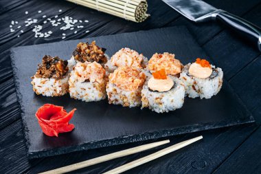 Suşi rulo siyah taş çubuklarla servis. Suşi koyu arka plan üzerinde görünümü kapatın. Geleneksel Japon mutfağı. Restoran, yemek menüsü, yemek tarifi, Cafe konsept. Kopya alanı sayesinde Live tarzı