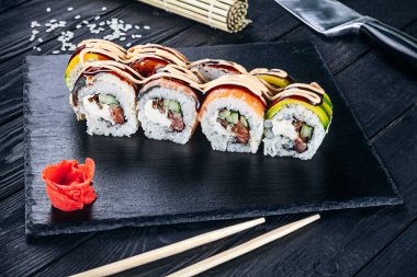 Suşi rulo siyah taş çubuklarla servis. Suşi koyu arka plan üzerinde görünümü kapatın. Geleneksel Japon mutfağı. Restoran, yemek menüsü, yemek tarifi, Cafe konsept. Kopya alanı sayesinde Live tarzı