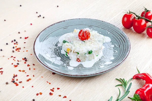 Close up view on risotto with cherry tomato, herps and spices on wooden background. Restaurant, food menu, recipe, cafe concept. Lifestyle with copy space. Italian cuisine.