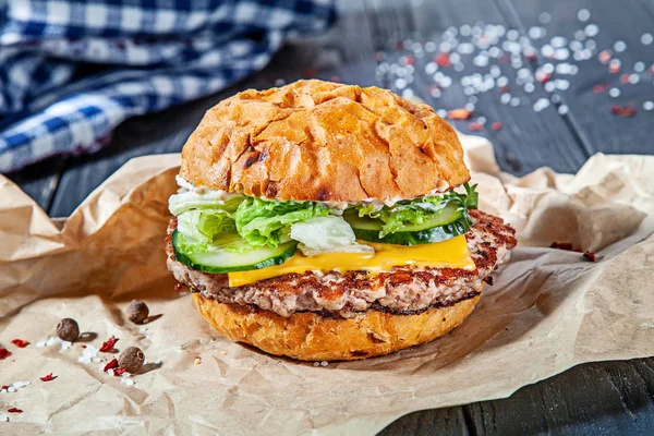 Fresh homemade burger with meat, sauce and vegetables on on wooden background. Close up view on american fast food. Restaurant, food menu, recipe, cafe concept. Lifestyle with copy space