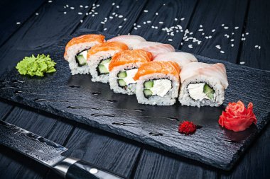 Koyu taş somon ile suşi rulo set zencefil ve wasabi ve ahşap siyah ahşap masa ile servis edilir. Taze Japon mutfağı. Asya yemekleri yakın görünüm. Menü için Sushi görüntüsü.