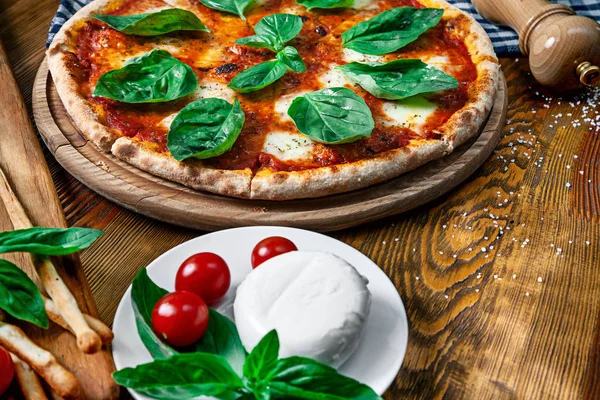 Close up view on fresh homemade margarita pizza with ingridients on wooden background. Mozzarella, basil, cherry tomato. Copy space for design. Picture for menu, italian cuisine — Stock Photo, Image