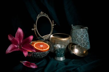 Koyu arka planda antika dekor öğeleri ile güzel sanat tarzı düşük anahtar hala hayat. Vazolar, çiçekler, ayna, tasarım alanı ile turuncu bileşimi. Dekoratif dükkan için görüntü