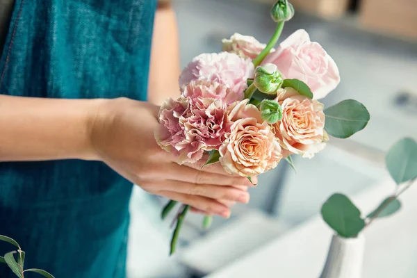 Cropped view on creative florist making flower bouquet in floral studio. Young female in workwear workplace. flower shop, business, sale and floristry concept. Copy space for design