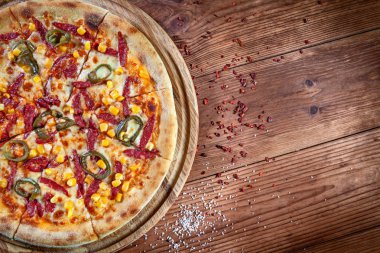 Logo veya tasarım için kopya alanı ile ahşap arka plan üzerinde taze İtalyan pizza üst görünümü. Biber, salam ve dekorasyon ile mısır ile Pizza. Düz lay gıda