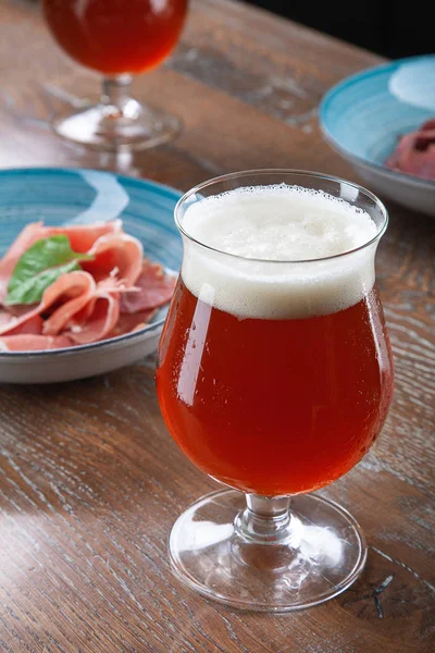 Vista da vicino sulla birra ambrata fredda in un bicchiere con spuntino al bar sul tavolo. Immagine a barre con spazio di copia per logo o marca. Bevande alcoliche rinfrescanti. Gustosi snack del ristorante — Foto Stock