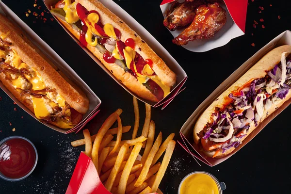 Widok z góry na Fast food. Tradycyjna amerykańska przekąska Hot Dog i frytki z widokiem na sosie z góry na ciemnym stole. Gourmet grillowane wszystkie psy wołowiny hots. Kopiuj przestrzeń — Zdjęcie stockowe