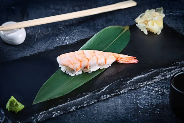 Close up view on served Nigiri with shrimp on dark plate on dark background with copy space. Delicious Ama Ebi Shrimp Nigiri Sushi. Traditional Japanese cuisine