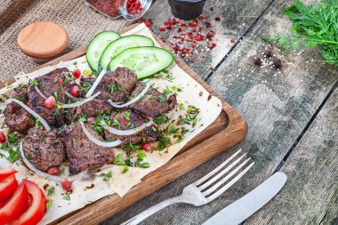 Yakın ızgara et (domuz) soğan, domates ve otlar, baharatlar ile pide ekmek servis. Ahşap arka planda geleneksel doğu shashlik veya kebap eti. kopya alanı ile yaz barbekü gıda