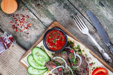 Üst görünüm ızgara et (domuz) soğan, domates ve otlar, baharatlar ile pide ekmek servis. Ahşap arka planda geleneksel doğu shashlik veya kebap eti. kopya alanı ile yaz barbekü gıda