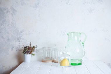 Limonata pişirmek için hazırlık. Taze, yaz serinletici içecek. Beyaz cocncrete arka planda su, cam ve limon ile karafe. Kopyalama alanı ile minimalizm. limonata yapmak. Yapmak için malzemeler