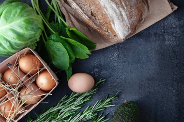 Yemek pişirmek için ingridients. Taze, organik sebzeler, glutensiz ekmek, eko yumurta ve maydanoz. kopya alanı ile koyu taş arka plan üzerinde bahar sebzeler. Düz yatıyordu. Sağlıklı gıda kavramı