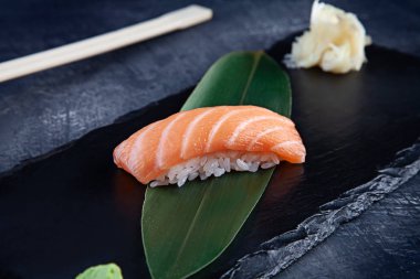 Kopya alanı ile karanlık arka plan üzerinde koyu plaka üzerinde somon ile sunulan Nigiri üzerinde görünümü kapatın. Lezzetli somon Nigiri Suşi. Geleneksel Japon mutfağı