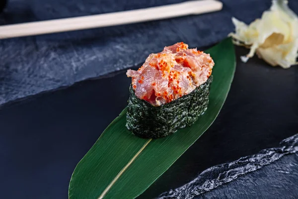 Close up view on gunkan sushi with spicy sauce and tuna on dark stone background. Fresh Japanese cuisine. asian food. Sushi image for menu. Seafood, healthy food. raw