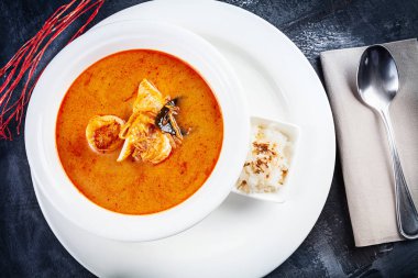 Tom yum çorba üst görünümü pirinç ile beyaz plaka servis. karides, deniz ürünleri, Hindistan cevizi sütü ve kase kopya alanında biber biber ile çorba. Geleneksel Tayland mutfağı. Kopya alanı olan öğle yemeği