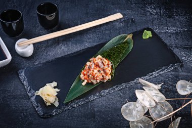 Yakından yemek balığı ve Tobico havyar ile lezzetli el rulo suşi yakın çekim soya sosu ve zencefil ile koyu taş plaka üzerinde servis. Kopya alanı. Temaki, Japon mutfağı. Sağlıklı gıda