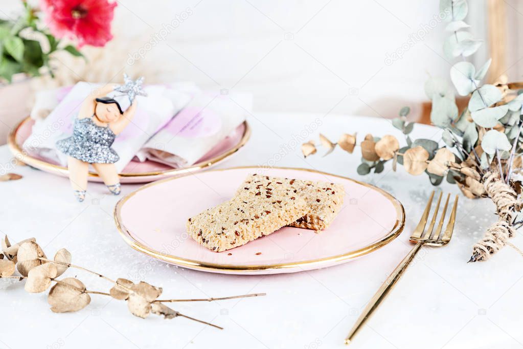 Veggie healthy Bars with tahini served on rose plate above white background. Close up horizontal food photo. Gluten free, healthy dessert. Vegan food and sweets. Snack. Copy space