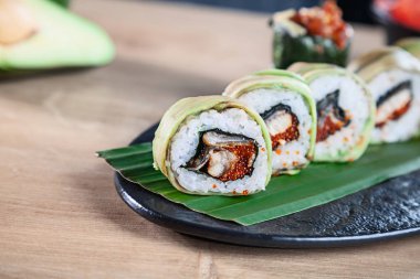 Suşi rulo seti yakın görünüm. Kaliforniya rulo somon, avokado ve havyar ahşap masada hizmet vermiştir. Japon mutfağı. Boşluk Kopyala. Menü için suşi servis edildi. Sağlıklı gıda, deniz ürünleri