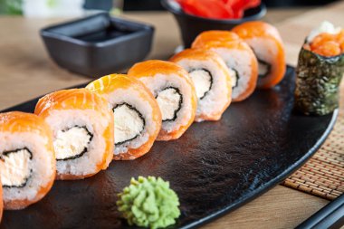 Suşi rulo seti yakın görünüm. Kaliforniya rulo somon, avokado ve havyar ahşap masada hizmet vermiştir. Japon mutfağı. Boşluk Kopyala. Menü için suşi servis edildi. Sağlıklı gıda, deniz ürünleri