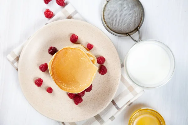 朝食には蜂蜜またはマープルシロップとベリーのトップビューパンケーキ。朝食に食べ物設計用のスペースをコピーします。自家製アメリカンパンケーキスナック。ミルクのグラスとパンケーキ — ストック写真