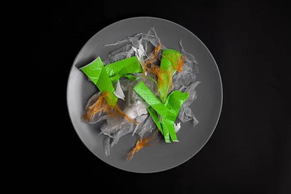 Concept poster for plastic pollution. Artwork plastic salad served on plate. Ban plastic concept. Ready to eat. food concept. View from above with copy space. Dark background