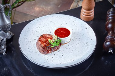 Beyaz tabakta kırmızı sos ile servis ızgara pişmiş sığır biftek küçük bir kısmını yakından görünümü. Öğle veya akşam yemeği için Amerikan yemeği. Yatay gıda arka plan. Kopyalama alanı.