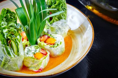 Yeşil soğan, karides ve kase krema ile yeşil bahar rulo görünümüne yakın. Seçici odak. Japon yemekleri. Suchi rulo. Deniz ürünleri. Öğle yemeği için balık. Sağlıklı, diyetli, dengeli yiyecekler. Pirinç kağıdı