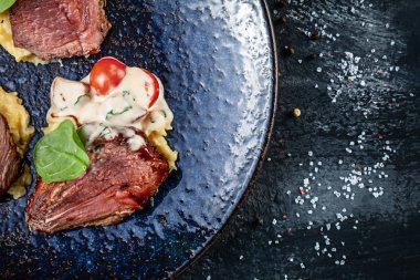 Domates ve patates püresi ile koyu tabaktabakta servis kan ile dilimlenmiş Sulu orta biftek yakından görünümü. Et yemeği. Amerikan yemekleri. Tasarım için kopyalama alanı