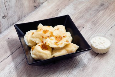 Koyu plaka üzerinde ekşi krem ile lahana veya patates ile köfte görünümü yakın ahşap masada duruyor. Ukraynalı yemek. Tasarım için alanı kopyalayın. Vareniki