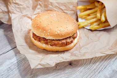 Zanaat kahverengi kağıt üzerinde patates kızartması ile tavuk burger görünümü yakın. Geleneksel Fast-Food. tavuk Chop ile taze lezzetli burger. Tasarım için alanı kopyalayın. Sağlıksız yiyecekler. Yağ