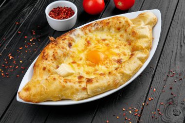 Baharatlar ile koyu arka planda görünüm Khachapuri yakın. peynir dolu ekmek geleneksel Gürcü çanak. Beyaz mutfak. Restoran yemeği. Adjarian 'daki Khachapuri. Peynir ve yumurta ile açık pasta