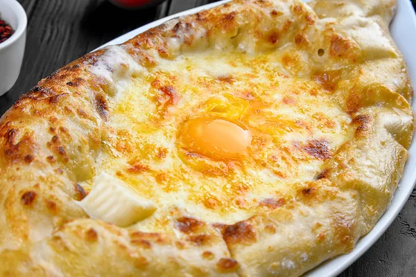 Vedere aproape Khachapuri pe fundal întunecat cu condimente. preparate tradiționale georgiene din pâine umplută cu brânză. Bucătărie caucaziană. Mâncare restaurant. Khachapuri în Adjarian. Deschideți plăcintă cu brânză și ou — Fotografie, imagine de stoc