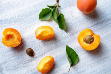 Kayısı ile Dikişsiz desen. Kayısı meyveleri ve yarısı mavi arka planda düz yatıyordu. Üst görünüm. Doğal, yeşil konsept. Boşluk Kopyala. Taze kesilmiş kayısı meyve dilimleri. Yaratıcı düzen. Gıda konsepti