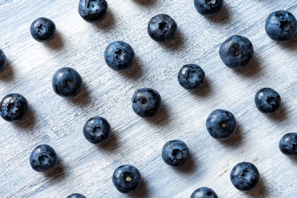 Färgglada mönster av blåbär på blå rustik bakgrund. Topputsikt, Flat Lay. Ekologiskt matkoncept. Kreativ layout gjord av blåbär. Färska sommar bär — Stockfoto