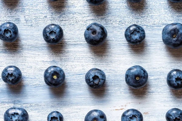 Färgglada mönster av blåbär på blå rustik bakgrund. Topputsikt, Flat Lay. Ekologiskt matkoncept. Kreativ layout gjord av blåbär. Färska sommar bär — Stockfoto