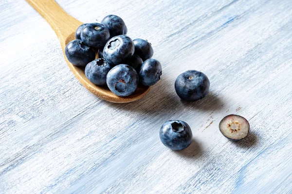 Vista superior en arándano en una cuchara de madera sobre fondo rústico azul. Concepto alimenticio de fruta natural. La mitad del arándano plano yacía. Diseño creativo. horizontal. espacio de copia — Foto de Stock