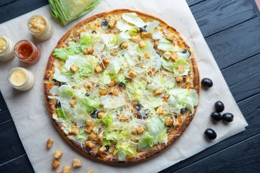 Koyu arka plan üst görünümünde ingridients ile lezzetli ev yapımı pizza. Düz chickeni, marul, kraker ve eritilmiş peynir ile pizza yatıyordu. Geleneksel İtalyan mutfağının yukarısındaki viw. Öğle yemeği için yemek