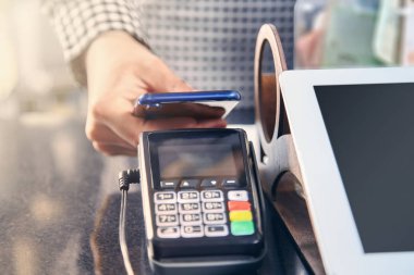 Cafe POS terminali aracılığıyla temassız ödeme görünümü yakın. Cashbox kavramı. Akıllı telefon ile ödeme. NFC teknolojisini kullanarak dükkanda Smartphone ile ödeme. Ticaret. Tonlu resim