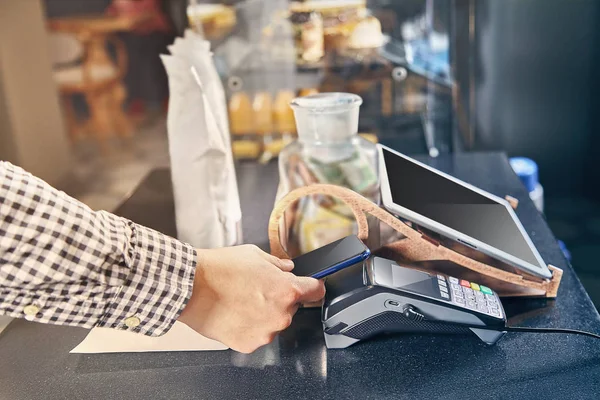 Vista de cerca del pago sin contacto a través de la terminal de punto de venta en la cafetería. Concepto Cashbox. Pagar con smartphone. pagar con smartphone en tienda utilizando la tecnología NFC. comercio. Imagen tonificada — Foto de Stock