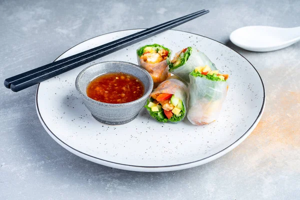 Close up Asian spring roll with chicken and red sauce. Pan-asian food. Street food concept with copy space. Grey background. Flat lay food for lunch or snack. healthy, balanced meal.